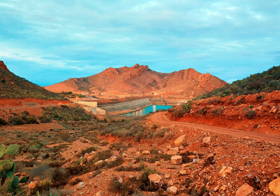 Morocco red desert landscape with small resevoir in background