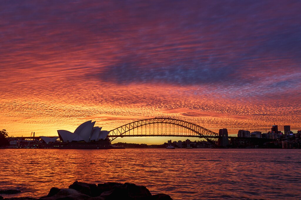 Silhouette of the Sydney Opera House against a pink and orange sunset