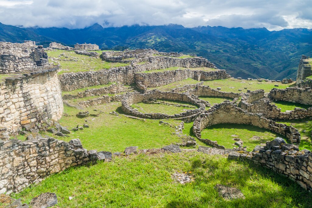 View of the ruins of round buildings in Kuélap, Peru, with mountains and cloud forest in the background