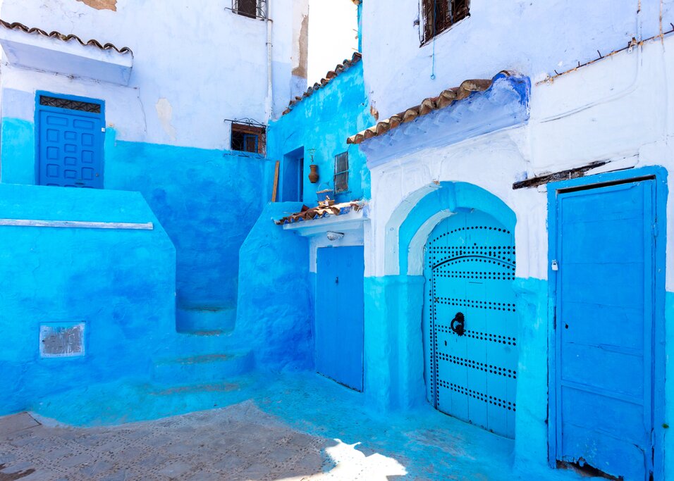 people walking through one of the beautiful streets with blue painted facades of the village of Chefchaouen