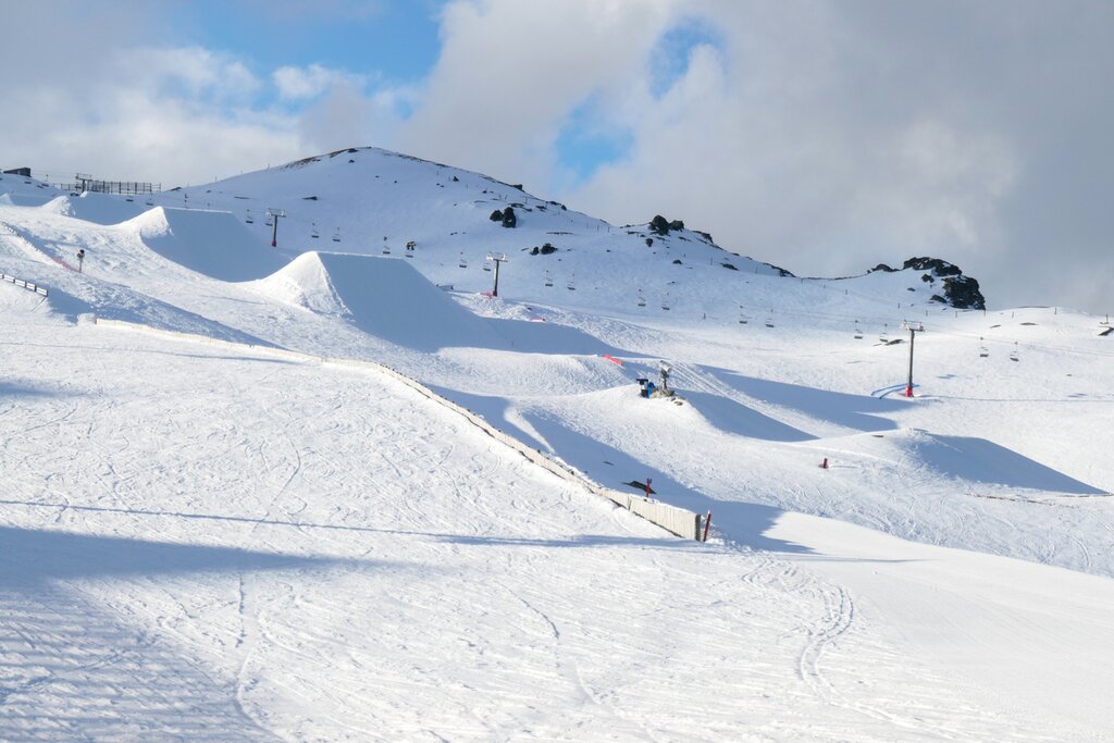 Cardrona ski field, located between Wanaka and Queenstown, after the ski lifts have closed and everyone has left. The ground is covered with ski tracks and footprints. Parts have already started to be smoothed over by snow ploughs, preparing for the next day. This image was taken at dusk in early Spring.