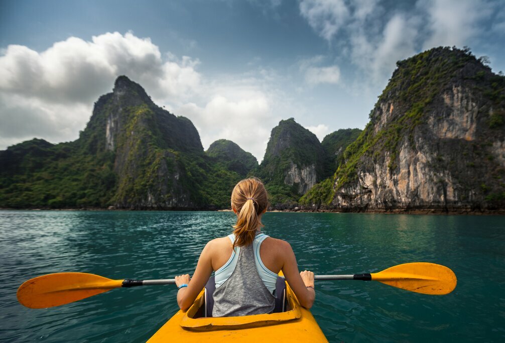 Take to a kayak and explore the limestone karts formations in Ha Long Bay