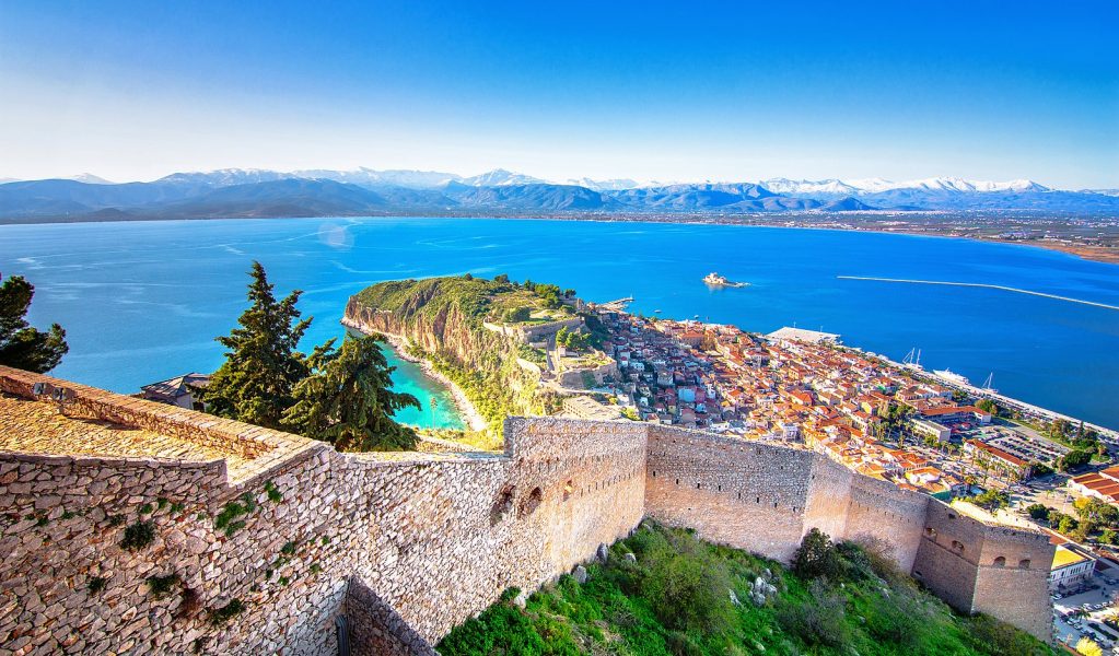 Old town of Nafplion in Greece view from above with tiled roofs, small port and bourtzi castle on the Mediterranean sea water